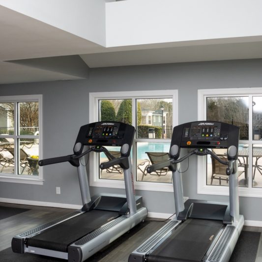 exercise room wall meets with the outdoor pool area and this view shows two treadmills